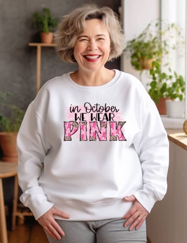 mature lady wearing a custom printed sweatshirt with text displaying we wear pink in October, supporting breast cancer awareness month